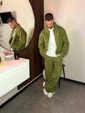 Uomo indossa completo coordinato streetwear verde oliva Clamont Wear, giacca zip e pantaloni baggy.