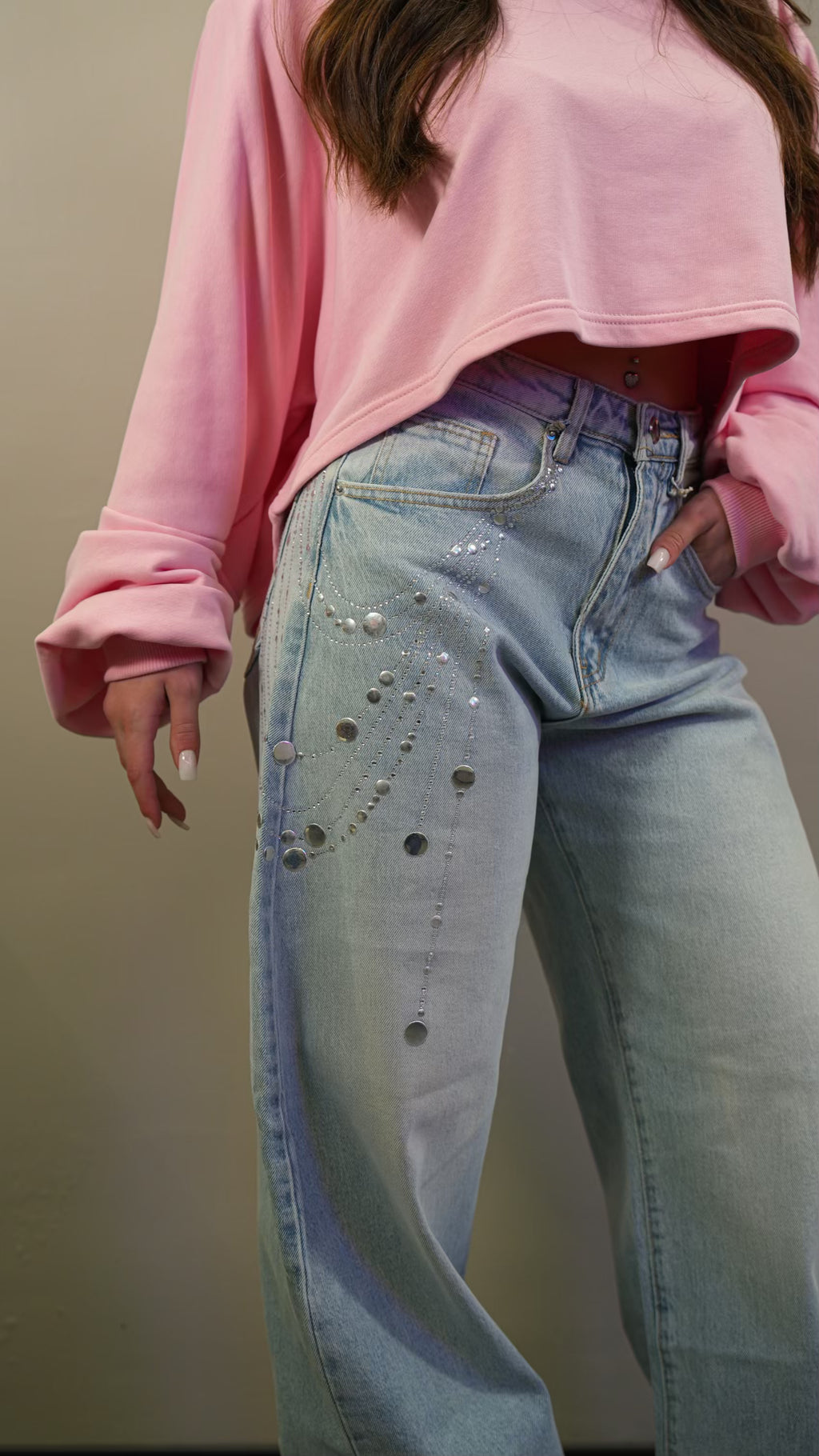Primo piano del tessuto denim dei Jeans Starlight che mostra il dettaglio delle applicazioni di strass, perle e punti luce sulla parte frontale della coscia.